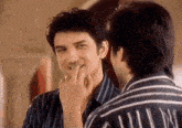 a man is touching his face while looking at himself in the mirror