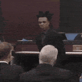 a man in a suit with dreadlocks stands in front of a podium