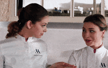 two women wearing white jackets that say carlo fortuna