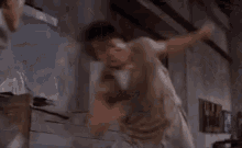 a person is jumping in the air in a room with a white cloth on their back .