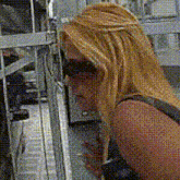 a woman wearing sunglasses and a tank top is looking at something