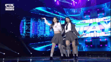 a group of girls are dancing on a stage in front of a large screen that says stay