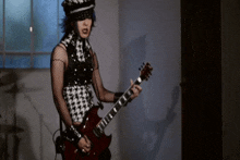 a woman is playing a red guitar in a room