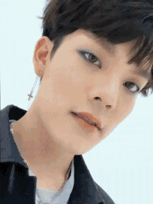 a close up of a person 's face with a cross earrings