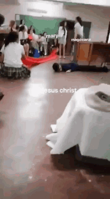 a group of people are in a classroom with jesus christ written on the floor .
