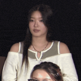 a woman wearing a white off the shoulder top and a necklace