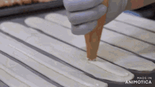 a person is spreading cream on a piece of dough with the words made in animotica in the corner
