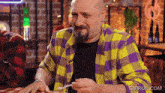 a man in a yellow and purple plaid shirt is eating with a fork