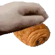 a close up of a person holding a croissant with a bite taken out of it .