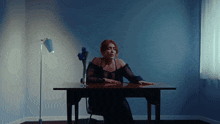 a woman sits at a table with a vase of blue flowers