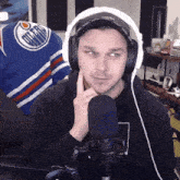 a man wearing headphones and a hat with an edmonton oilers jersey behind him