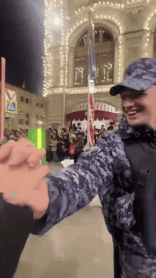 a man in a military uniform is giving a high five to another person
