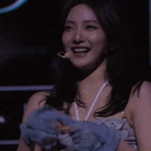 a woman in a blue dress is smiling and covering her eyes with a blue cloth