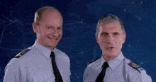 two men in uniform are standing next to each other and smiling .