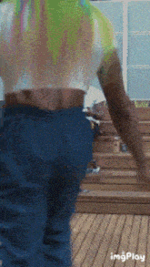a person wearing a tie dye shirt and blue jeans is walking on a wooden deck ..