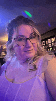 a woman wearing glasses and a purple dress is taking a selfie