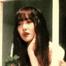 a woman with long hair and bangs is looking out a window .