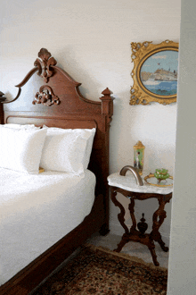 a bed with white sheets is next to a small table