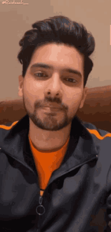a man with a beard is wearing an orange shirt