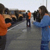 a group of people standing on a sidewalk in front of buses