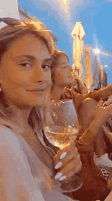 a woman is sitting at a table with a glass of wine in her hand .