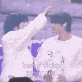 a couple of people are standing next to each other and one of them is putting a sticker on the other 's head .
