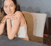 a woman is sitting at a table with her hands on her shoulder and smiling at the camera .