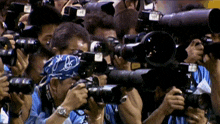 a man wearing a blue bandana takes a picture with a nikon camera