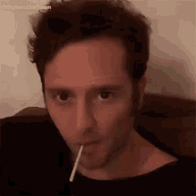 a man is holding a lollipop in his mouth .