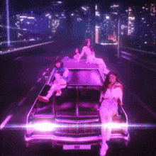 three women are sitting on top of a purple car with a license plate that says iiii
