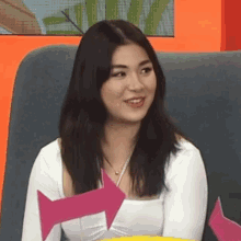 a woman is sitting on a couch with a pink arrow pointing to the left