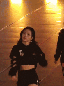 a woman in a black crop top is dancing on a stage in front of a crowd .