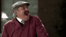a man with a mustache is wearing a hat and a red jacket .