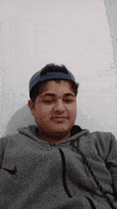 a young man wearing a nike hoodie and a blue hat looks at the camera