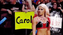 a woman is holding a sign that says carol in front of a crowd