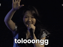 a woman singing into a microphone with the word tolooongg written in white