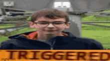 a boy with glasses is standing in front of a sign that reads triggered