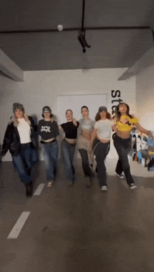 a group of women are dancing in a room with a sign on the wall that says studios