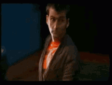 a blurry picture of a man in an orange shirt and jacket