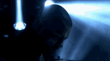 a man in a dark room with a blue light shining on his head