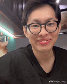 a man wearing glasses and a black shirt with the hashtag huwye_tawg on the bottom