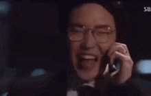 a man in glasses is talking on a cell phone .