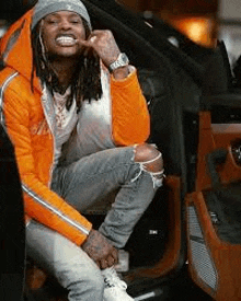 a man with dreadlocks is sitting in the back of a car and smiling .