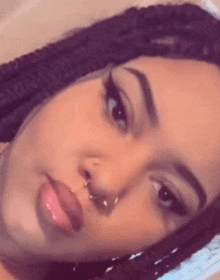 a close up of a woman 's face with a nose ring and dreadlocks .