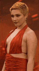a woman with short blonde hair is wearing a very plunging red dress