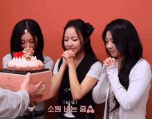 a woman blowing out a candle on a cake with a box that says ' g ' on it