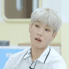a young boy with white hair and a plaid shirt looks at the camera with his mouth open