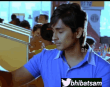 a man in a blue shirt is sitting in a restaurant with a twitter logo on his shirt