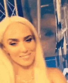 a woman with blonde hair is smiling and looking at the camera while standing in front of a mirror .
