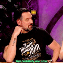 a man with a tattoo on his arm is wearing a mighty jein shirt